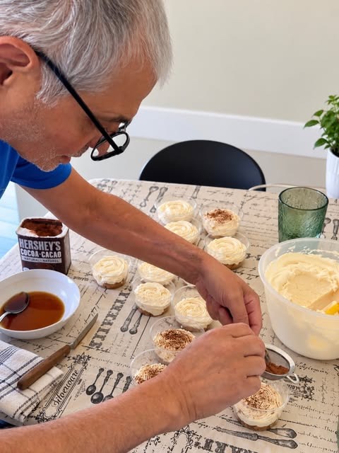 Tiramisu cups being dusted with cocoa